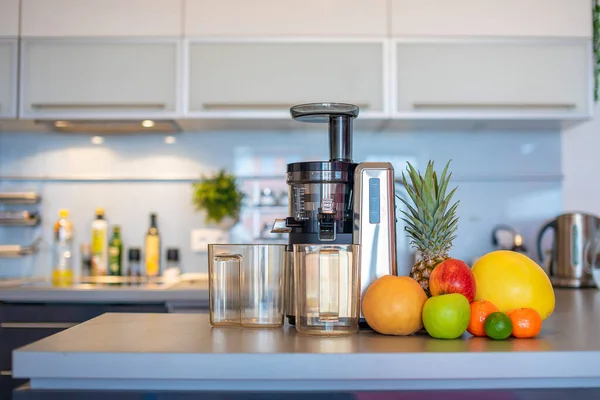 Fazendo suco de frutas com máquina de espremedor na cozinha doméstica, conceito de estilo de vida saudável — Fotografia de Stock