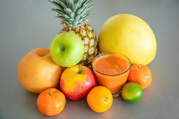 Gri arka planda farklı tropikal meyveler ve portakal suyu, sağlıklı beslenme tarzı konsepti. — Stok fotoğraf