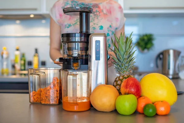 Женщина делает фруктовый сок с помощью соковыжималки машина на домашней кухне, здоровое питание концепции образа жизни — стоковое фото