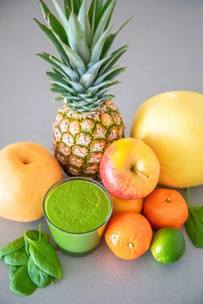 Gri arka planda farklı tropikal meyveler ve yeşil smoothie, sağlıklı beslenme tarzı konsepti — Stok fotoğraf