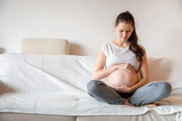 Junge schwangere Frau sitzt auf Sofa — Stockfoto