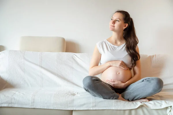 Junge schwangere Frau sitzt auf Sofa — Stockfoto