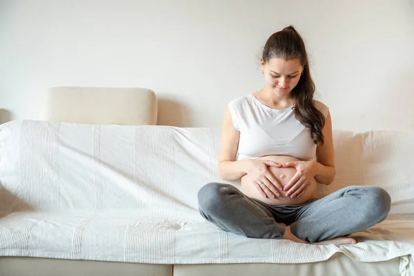 Junge schwangere Frau sitzt auf Sofa — Stockfoto
