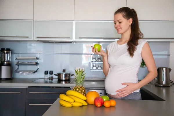 Schwangere und verschiedene tropische Früchte in der heimischen Küche — Stockfoto
