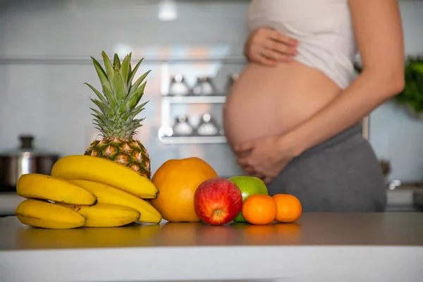 Schwangere und verschiedene tropische Früchte in der heimischen Küche — Stockfoto