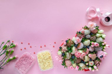El yapımı çikolata kaplı çilekler, çiçekler ve pembe arka planda tatlı pişirmek için dekorasyon.
