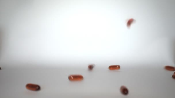 Fallende Flüssigkapseln aus Omega-oder Fischöl auf weißem Hintergrund — Stockvideo
