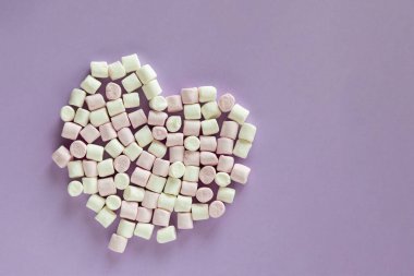 Mor arka planda kalp şeklinde şekerlemeler, yazı için boş alan, tatlı yiyecekler.