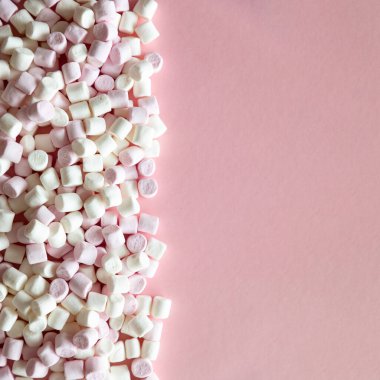 Pembe arka planda pembe ve beyaz mini marşmelovların arkaplan veya dokusu ve metin için boş alan