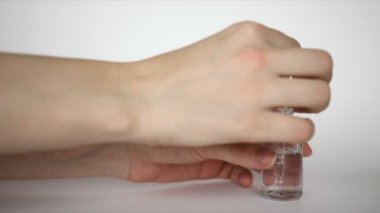 Hyaluronic acid drop falls from cosmetic pipette on hand, woman rubs funds hand on white background