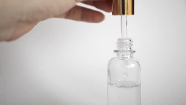 Gota de ácido hialurônico cai da pipeta cosmética no fundo branco, Dropper glass Bottle Mock-Up — Vídeo de Stock