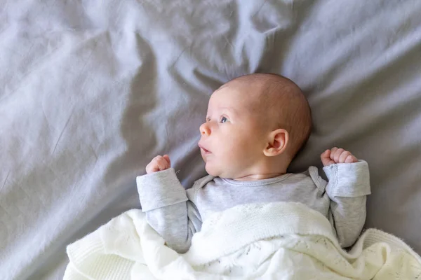 Retrato de cerca de un hermoso bebé de un mes sobre una manta gris — Foto de Stock