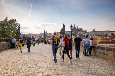Prag, Çek Cumhuriyeti - 8.05.2020: Karantina sırasında Çek Cumhuriyeti 'nin Prag kentindeki Charles Köprüsü boyunca yürüyen maskeli insanlar