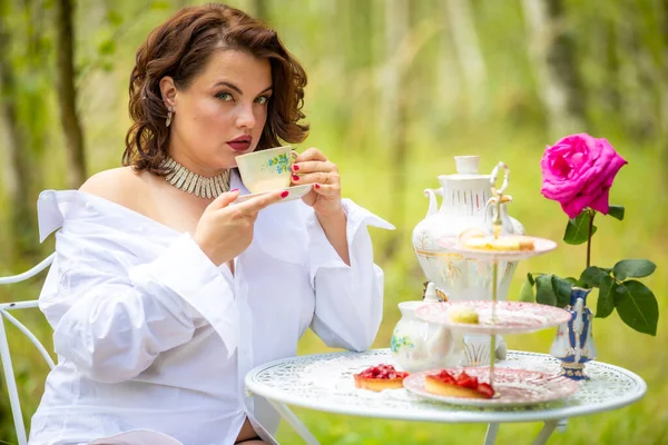 Woman is drinking coffee in the morning on the nature background of deep forest, morning of the bride, natural beauty