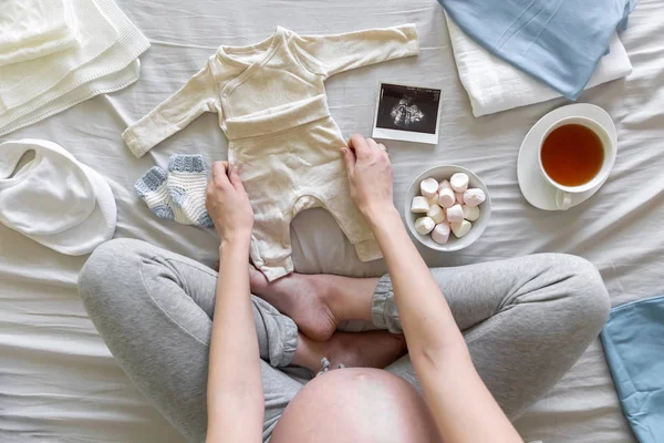 Vue Du Dessus De La Femme Enceinte Dans Le Lit Preparant Des Vetements Pour Bebe Garcon A La Maison Concept De Grossesse Et De Naissance L Amour Exploitation Stock Photo