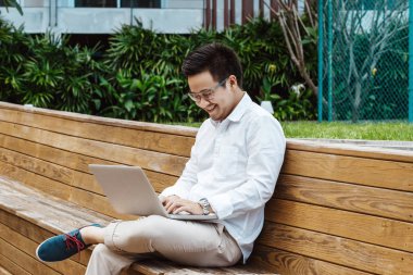 Garden'da dizüstü bilgisayarda çalışan genç mutlu işadamı