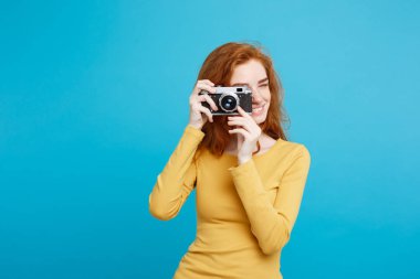 Seyahat ve insanlar kavramı - mutlu ifade vintage fotoğraf makinesi ile oynarken mutlu Kızıl kızıl saçlı kız portresi Headshot. Pastel mavi arka plan. Kopya alanı.