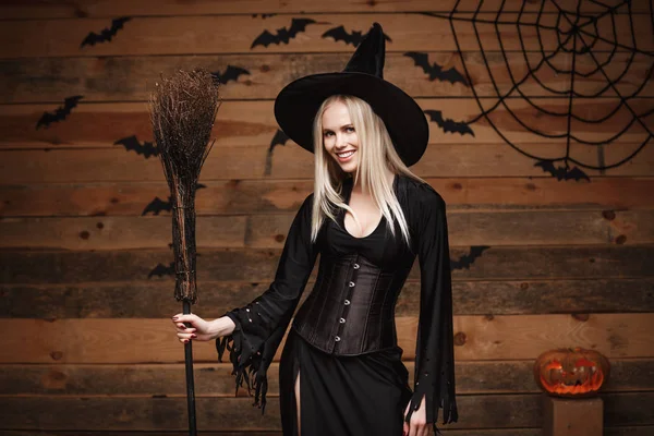 Concepto de bruja de Halloween - Feliz Halloween Sexy Witch posando sobre un viejo fondo de estudio de madera . — Foto de Stock