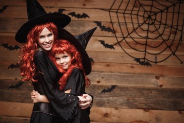 Cadılar Bayramı kavramı - güzel beyaz anne ve kızıyla birlikte uzun kızıl saçlı cadı kostümleri mutlu gülümseyerek ve birbirlerine sarılmak.