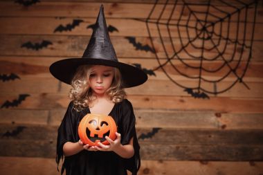 Halloween cadı kavramı - küçük beyaz cadı çocuk hayal kırıklığı ile Cadılar Bayramı Şeker kabak kavanoza şeker yok. yarasa ve örümcek web arka plan üzerinde.