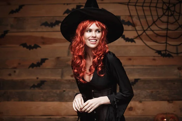 Halloween heks concept - Happy Halloween rode haren Witch holding poseren over oude houten studio achtergrond. — Stockfoto