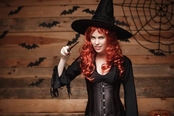 Halloween heks concept - Happy Halloween rode haren Witch holding poseren met toverstaf over oude houten studio achtergrond. — Stockfoto