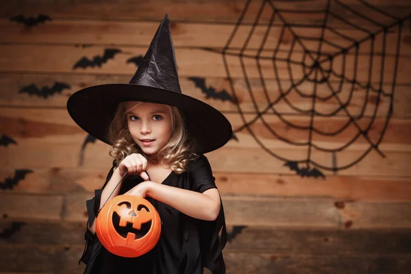 Koncepcja Witch Halloween - małe dziecko kaukaski czarownica cieszyć się z halloween dynia słoik. bat i spider web tle. — Zdjęcie stockowe