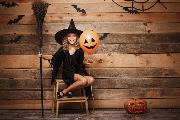 Halloween boszorkány koncepció - teljes hosszúságú lövés jelentő mágikus seprű és a léggömb felső denevér és a spider web háttér kaukázusi boszorkány, kisgyermek.. — Stock Fotó