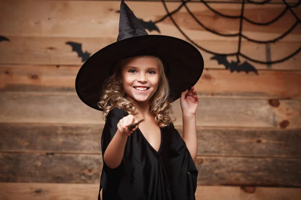Halloween boszorkány koncepció - kis boszorkány gyermek Élvezze játszik a varázspálca. bat és a spider web háttér felett. — Stock Fotó
