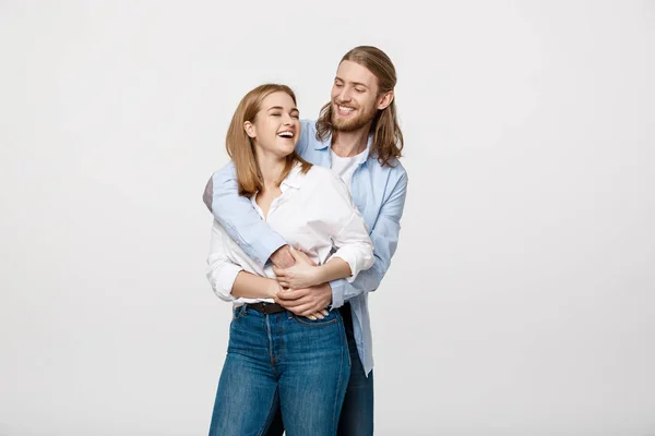 Retrato de alegre jovem casal de pé e abraçando uns aos outros no fundo branco isolado — Fotografia de Stock