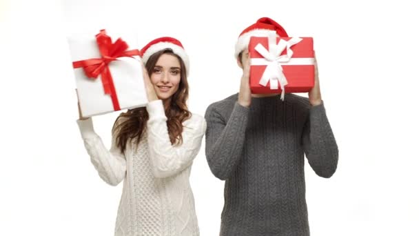4k junges Paar spielt und versteckt sich hinter Weihnachtsgeschenkbox auf weißem isolierten Hintergrund. — Stockvideo