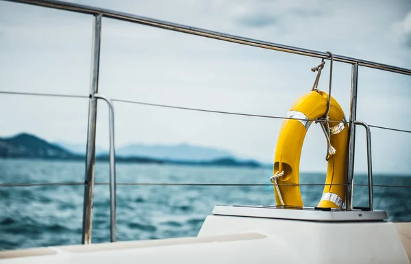 Close-up Yellow life ring hanging on boat with ocean background.