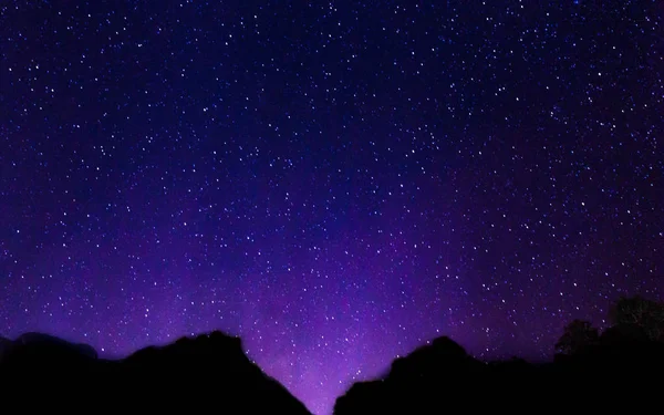 Ночное небо с множеством блестящих звезд с размытым горным фоном . — стоковое фото