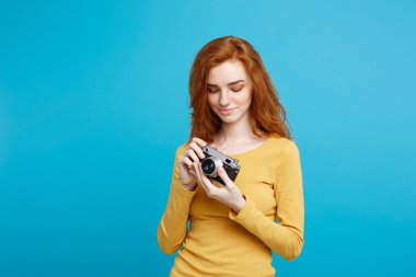 Seyahat ve insanlar kavramı - Headshot portre mutlu Kızıl kızıl saçlı kızın vintage fotoğraf makinesi ile mutlu ifade harekete hazır. Pastel mavi arka plan. Kopya alanı.