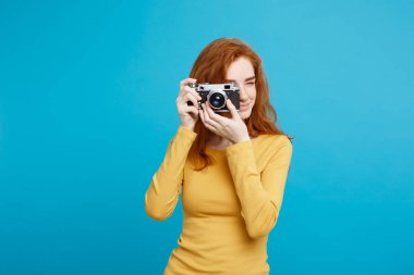 Seyahat ve insanlar kavramı - Headshot portre mutlu Kızıl kızıl saçlı kızın vintage fotoğraf makinesi ile mutlu ifade harekete hazır. Pastel mavi arka plan. Kopya alanı.