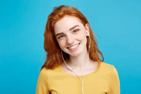 Conceito de estilo de vida - Retrato de alegre feliz ruiva menina de cabelo vermelho gosta de ouvir música com fones de ouvido alegre sorrindo para a câmera. Isolado no fundo azul pastel. Espaço de cópia . — Fotografia de Stock