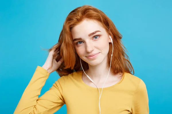 Conceito de estilo de vida - Retrato de alegre feliz ruiva menina de cabelo vermelho gosta de ouvir música com fones de ouvido alegre sorrindo para a câmera. Isolado no fundo azul pastel. Espaço de cópia . — Fotografia de Stock