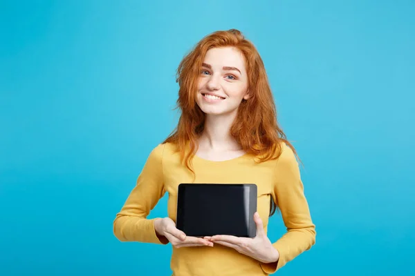 Nahaufnahme Porträt junge schöne attraktive Rothaarmädchen lächelnd zeigt digitale Tablet-Bildschirm auf schwarz. blauer Pastellhintergrund. Kopierraum. — Stockfoto