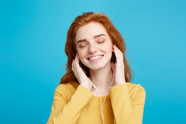 Conceito de estilo de vida - Retrato de alegre feliz ruiva menina de cabelo vermelho gosta de ouvir música com fones de ouvido alegre sorrindo para a câmera. Isolado no fundo azul pastel. Espaço de cópia . — Fotografia de Stock