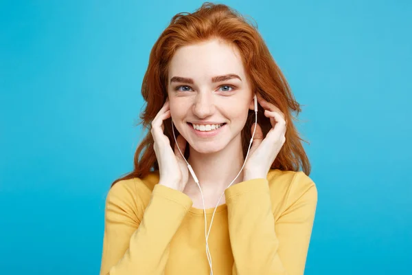 Conceito de estilo de vida - Retrato de alegre feliz ruiva menina de cabelo vermelho gosta de ouvir música com fones de ouvido alegre sorrindo para a câmera. Isolado no fundo azul pastel. Espaço de cópia . — Fotografia de Stock