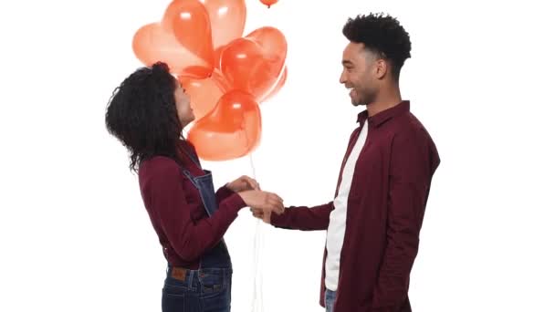 Slow motion joven guapo afroamericano sorprender a su novia con el corazón globo en blanco fondo del estudio . — Vídeo de stock