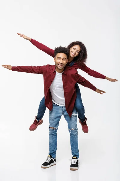 Full length young attractive african american lady riding back on her boyfriend back and enjoy playing to each other. — Stock Photo, Image