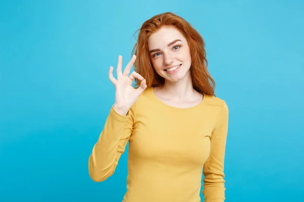 Fun and People Concept - Effigie Ritratto di affascinante ragazza dai capelli rossi rossicci con lentiggini che sorridono e fanno segno ok con il dito. Sfondo blu pastello. Copia spazio . — Foto Stock
