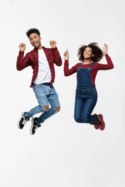 Estilo de vida, felicidad y concepto de personas: Feliz joven encantadora pareja afroamericana saltando sobre fondo gris brillante . —  Fotos de Stock