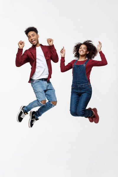 Lifestyle, happiness and people concept: Happy young lovely African American couple jumping over bright grey background
.