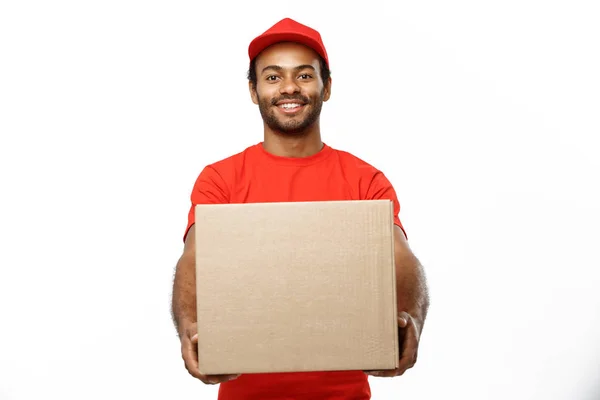 Conceito de entrega - Retrato de homem de entrega afro-americano feliz em pano vermelho segurando um pacote de caixa. Isolado no estúdio branco Background. Espaço de cópia — Fotografia de Stock