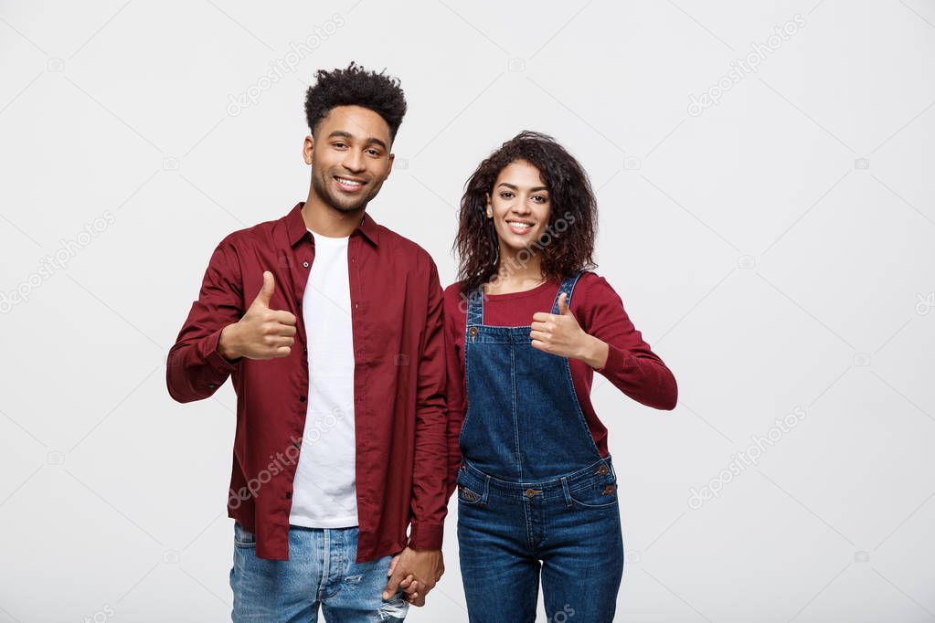 Portrait of attractive African american couple showing thumb up over white studio background.