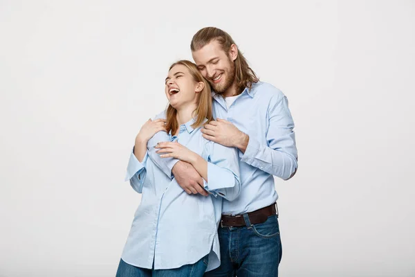 Πορτρέτο του χαρούμενα νεαρό ζευγάρι που στέκεται και να αγκαλιάζονται μεταξύ τους σε απομονωμένα άσπρο φόντο — Φωτογραφία Αρχείου