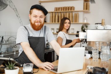 Kahve iş kavramı - sakallı genç yakışıklı bartende, barista veya Yöneticisi çalışma ve laptop modern kahve dükkanında planya.