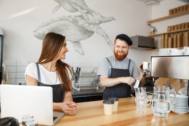 Kahve iş kavramı - pozitif genç sakallı dostum ve güzel çekici Bayan barista çift birlikte modern kahve dükkanında çalışmaktan hoşlanıyor